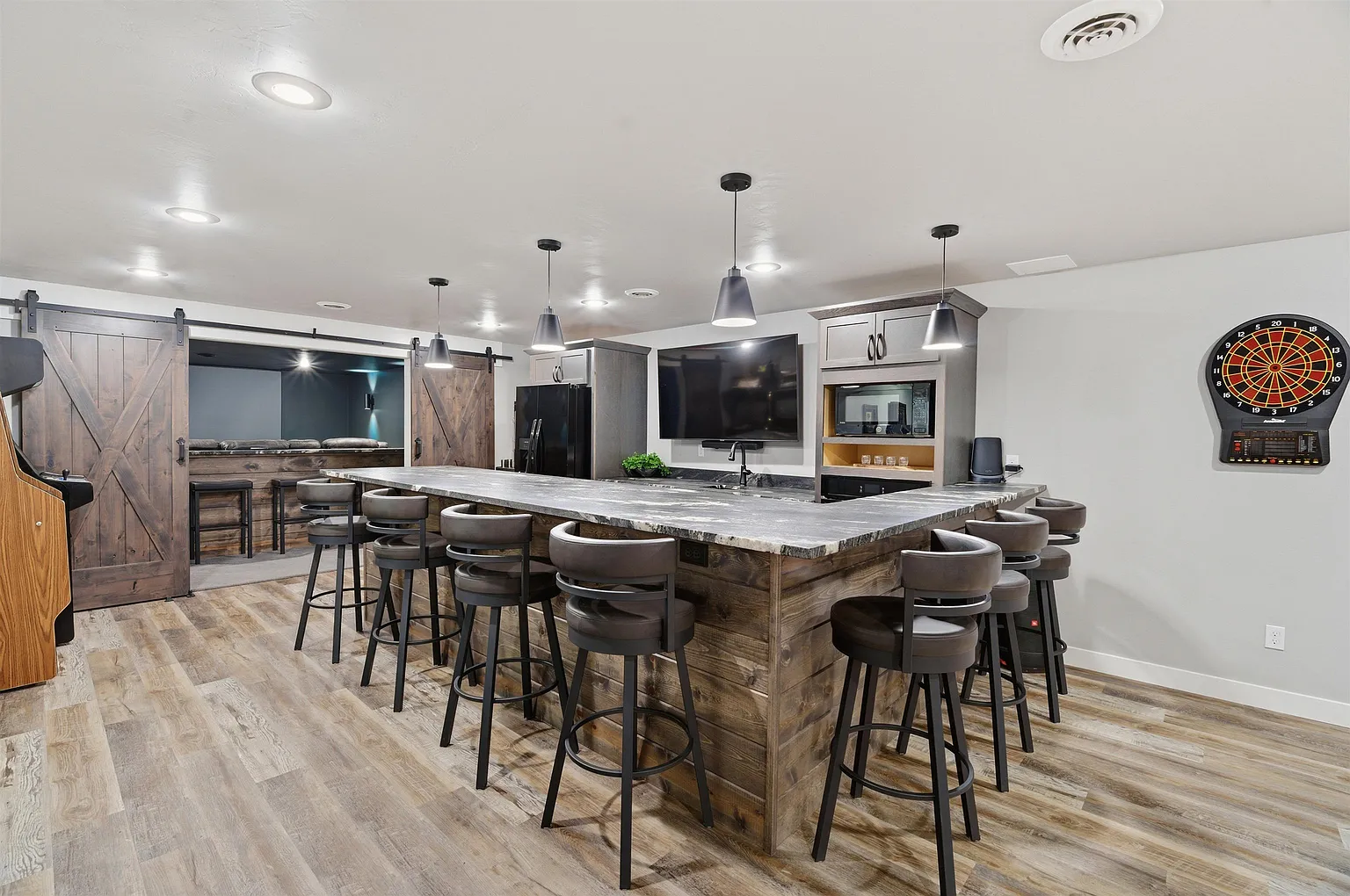 Long bar with swivel stools, dartboard, and theater barn doors