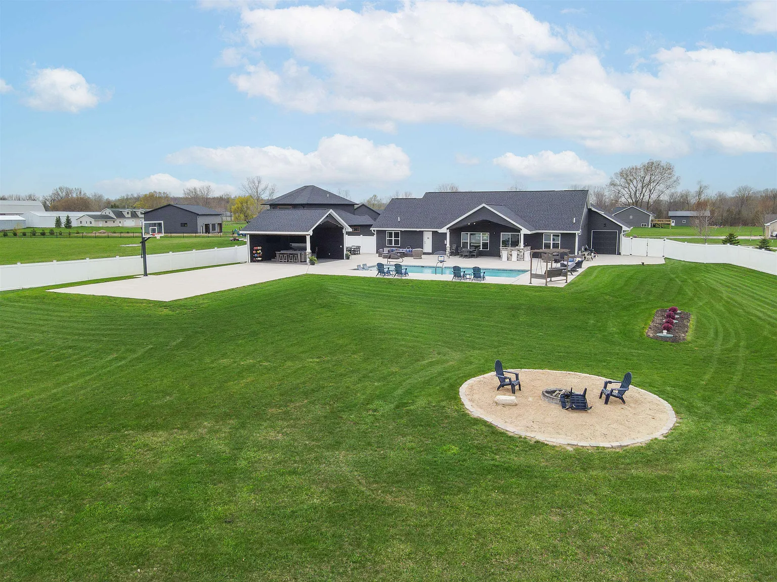 Aerial view of backyard with pool, sport court, and fire pit